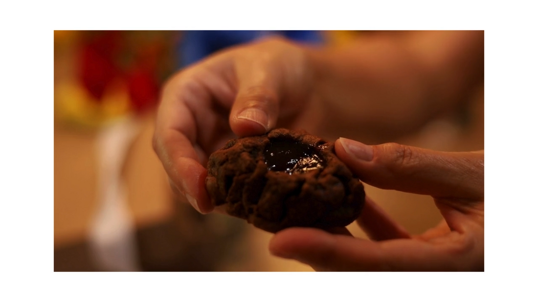 Hand Grabbing Lava Cookie and breaking it open, showing the texture of the raspberry lava and triple-chocolate cookie
